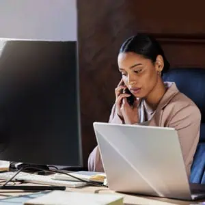 Woman on phone with laptop, symbolizing the importance of contacting a personal injury attorney - Gennusa Firm