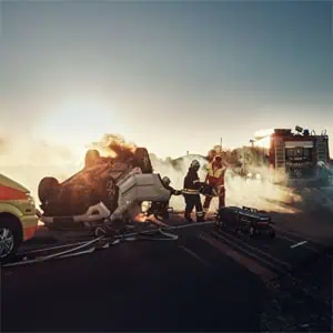 A man stands beside a burning car, symbolizing the catastrophic injury